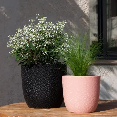 Vases of different sizes, one larger black and one smaller pink. Both have a wrinkled surface created with the mold